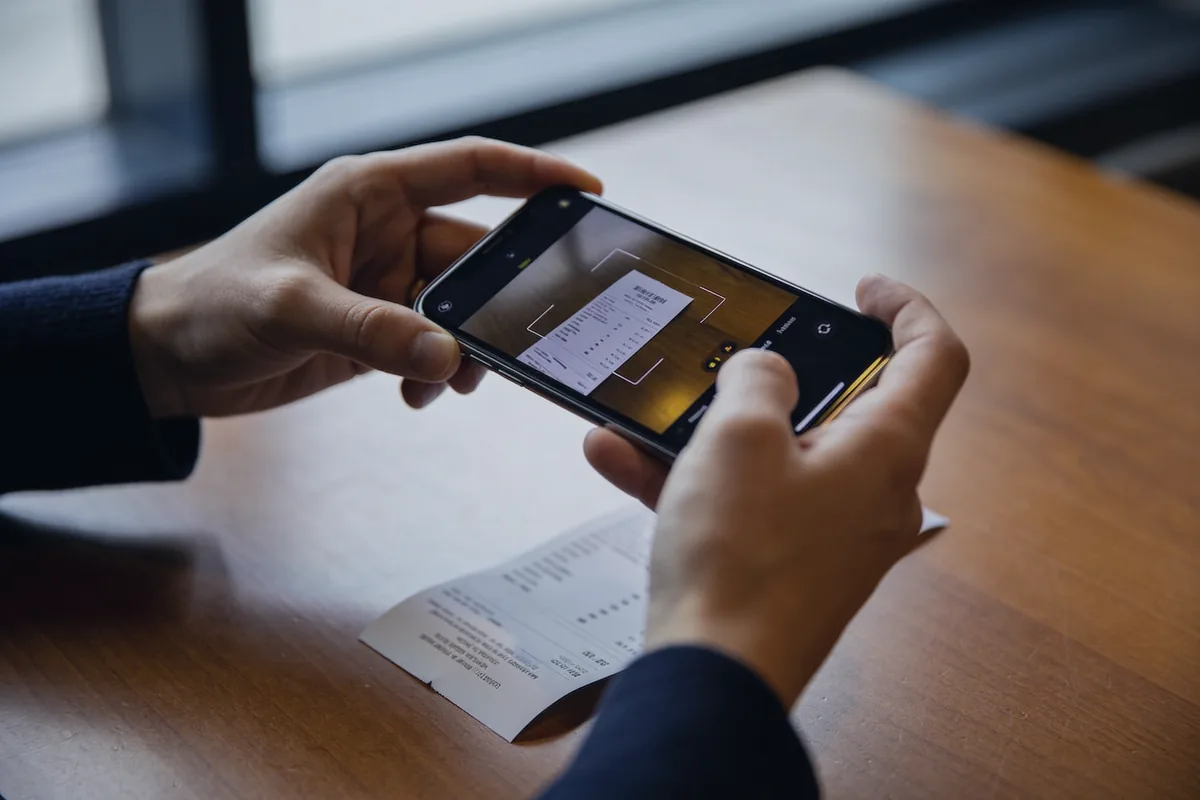 Ein Papierbeleg wird mit dem Smartphone abfotografiert und digital erfasst.